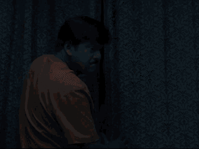a man in a yellow shirt is standing next to a woman in a white dress behind a curtain