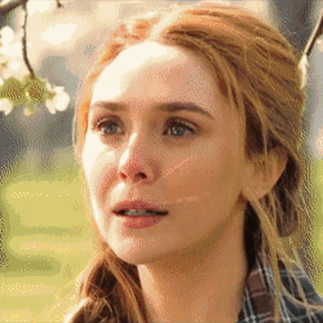 a close up of a woman 's face with a plaid shirt on .