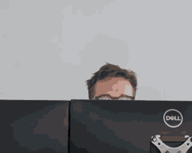 a man wearing glasses is sitting in front of a dell computer monitor
