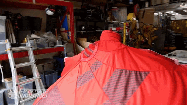 a red umbrella in a garage with the words hacksmith industries visible