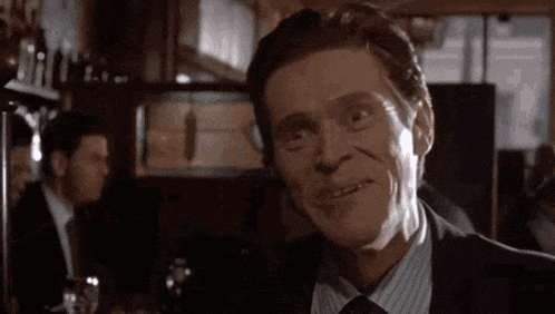 a man in a suit and tie is making a funny face in front of a bar .