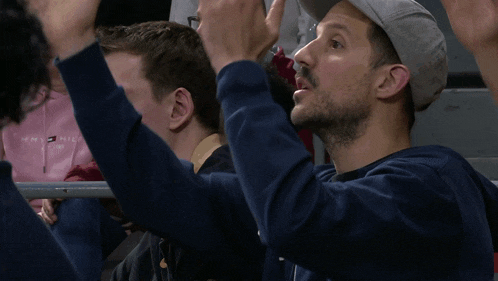 a man wearing a tommy hilfiger sweatshirt holds his hands up