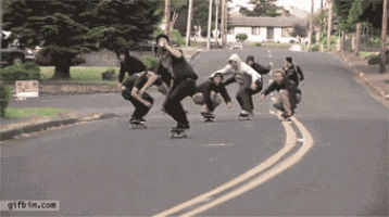 a group of people riding skateboards down a street with gifbin.com at the bottom of the image