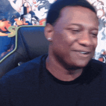 a man in a black shirt is smiling in front of a cartoon wall