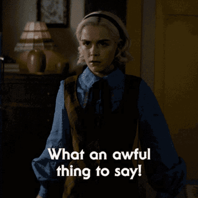 a woman in a blue shirt is standing in a dark room and says what an awful thing to say