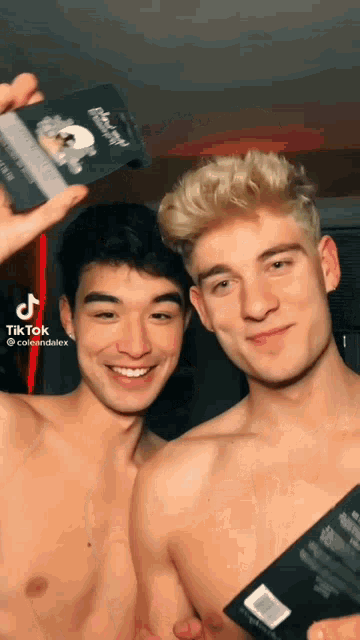 two shirtless men are posing for a picture and one of them is holding a black box that says ' black knight ' on it