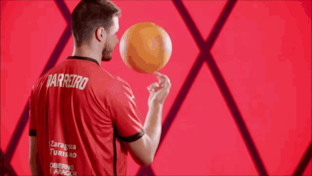 a man in a zaragoza tourism jersey holds a basketball in his hand
