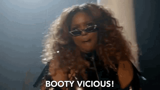 a woman with curly hair is wearing sunglasses and a choker and says booty vicious .
