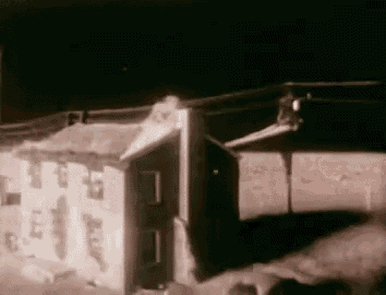 a black and white photo of a house being destroyed by a fire .