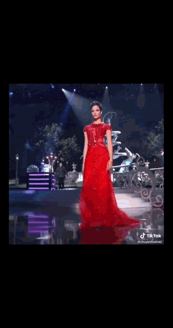 a woman in a red dress is walking on a stage with a tiktok logo in the corner