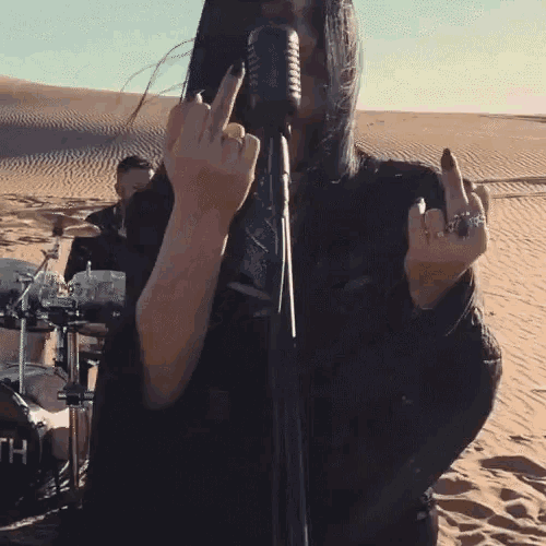 a woman singing into a microphone with her middle finger up