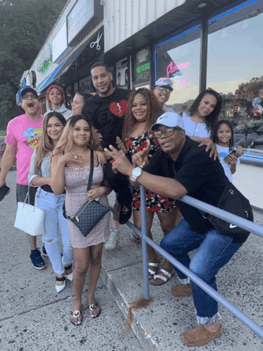 a group of people are posing for a picture in front of a store that has a neon sign that says flower shop