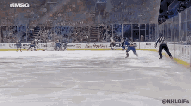 a hockey game is being played in a stadium with advertisements for tim hortons on the ice .