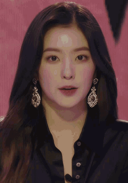 a close up of a woman wearing earrings and a black shirt with her eyes closed