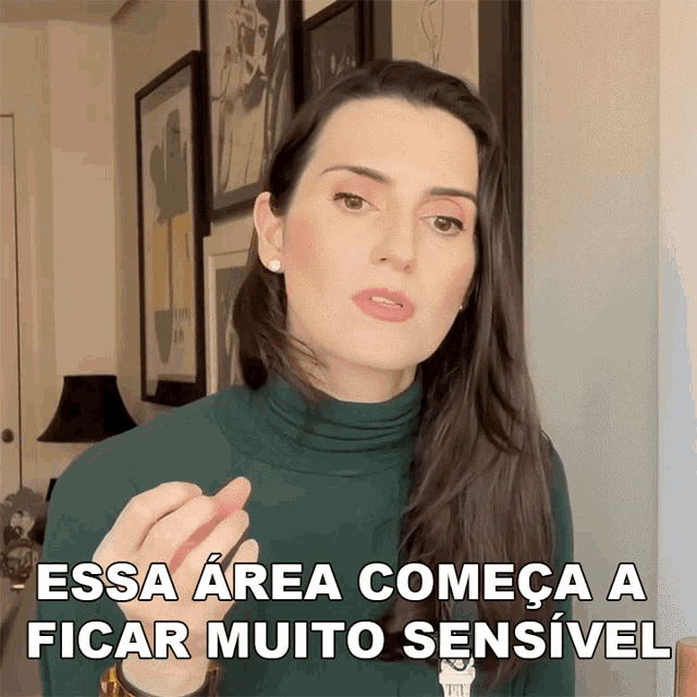 a woman in a green turtleneck says " essa area começa a ficar muito sensivel "