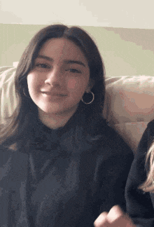 a young woman is sitting on a couch wearing hoop earrings .