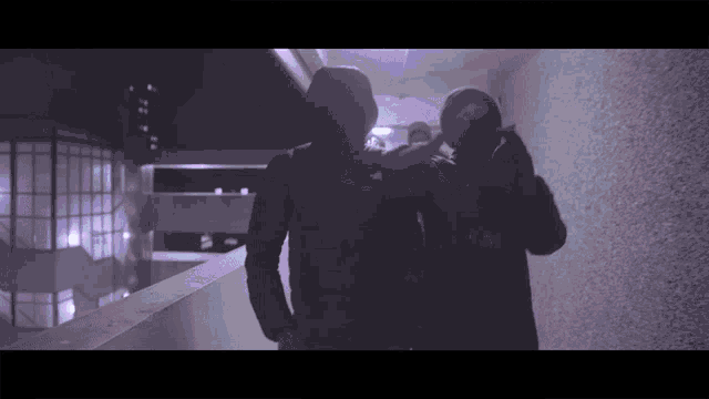 a man wearing a hoodie that says ' adidas ' on it is standing next to another man