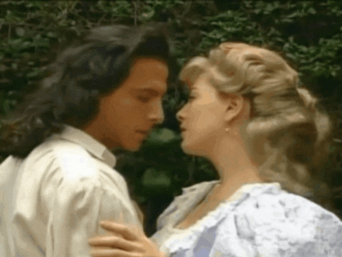 a man and a woman are kissing each other in a park .