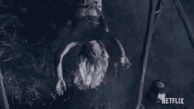 a woman is hanging upside down from a rope while a man looks on ..