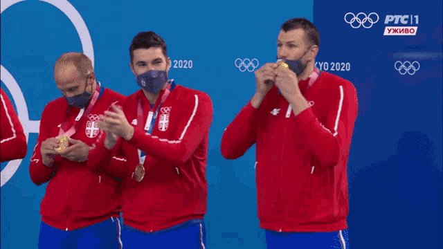a group of men wearing face masks and medals are clapping in front of a sign that says ptc 11