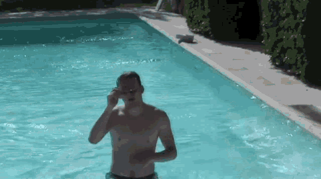 a shirtless man wearing goggles is standing in a pool