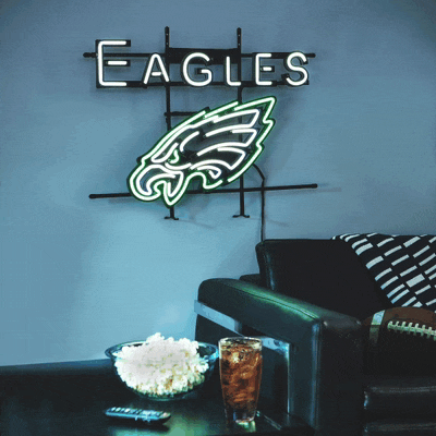 a neon sign for the eagles hangs on a wall above a couch