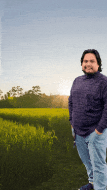 a man in a purple shirt stands in a field