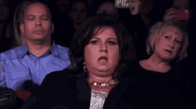 a woman is making a funny face while pointing at something .