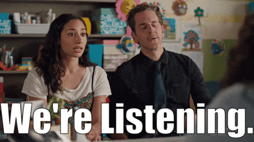 a man and a woman sitting at a table with the words " we 're listening " behind them