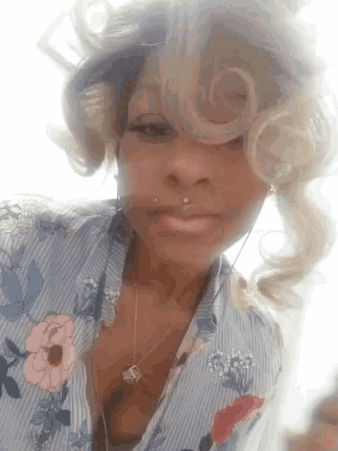 a woman wearing a floral shirt and a necklace with a letter s on it