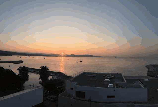 a sunset over a body of water with boats in the distance