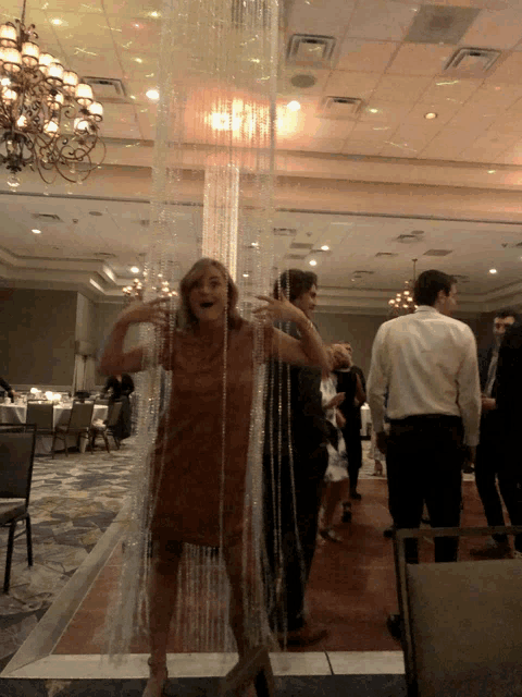 a woman in a brown dress is standing in front of a curtain