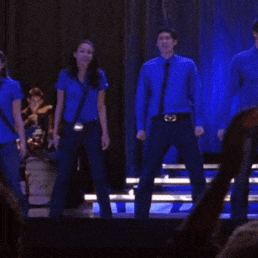 a group of people standing on a stage with a drum set in the background