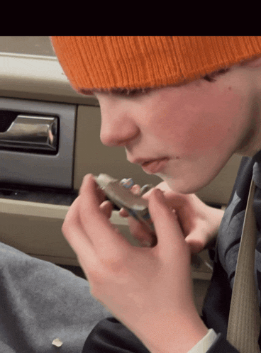 a young boy wearing an orange hat is looking at something