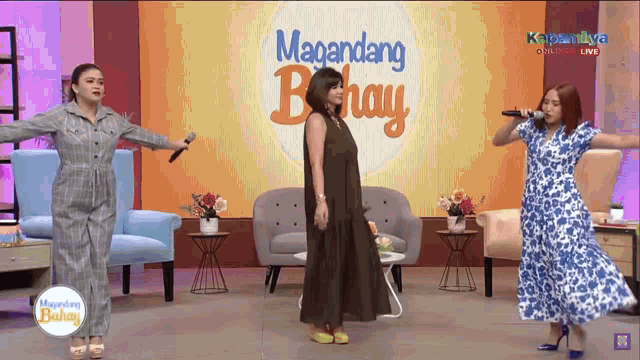 three women singing on a stage in front of a magandang buhay sign