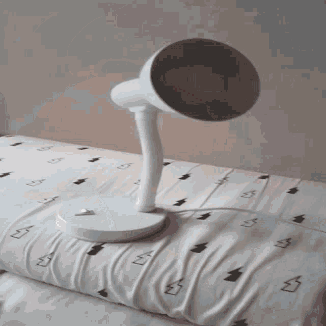 a white lamp is sitting on a bed with a lightning bolt patterned sheet
