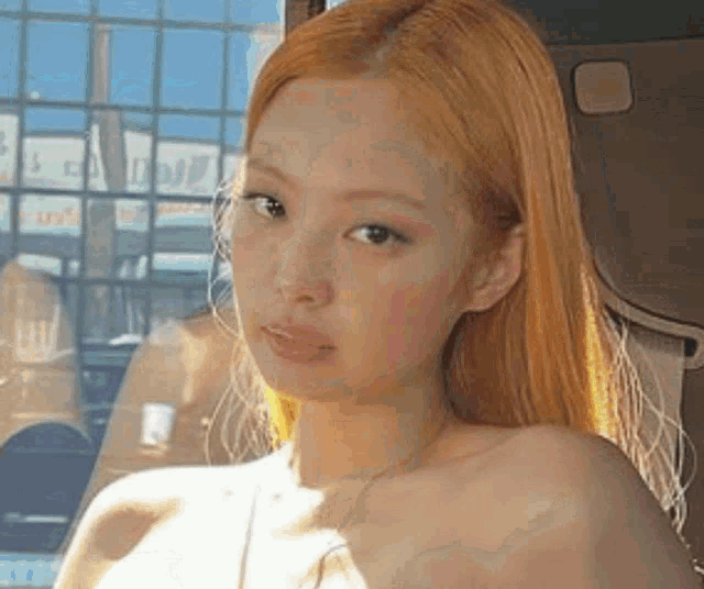 a close up of a woman with blonde hair sitting in a car looking at the camera .