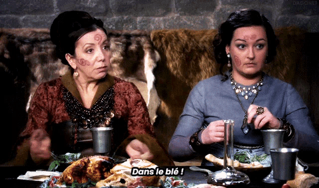 two women are sitting at a table with a turkey and the words dans le ble on the table