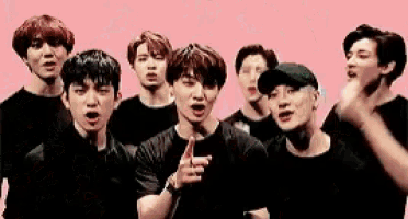 a group of young men are standing next to each other on a pink background and making funny faces .