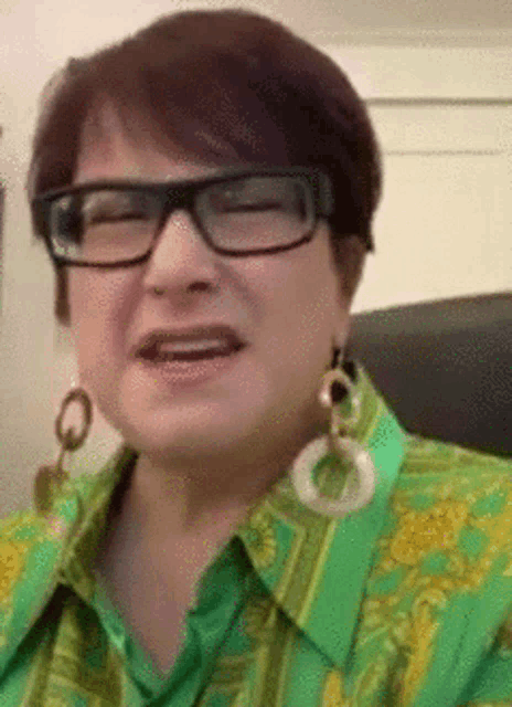 a woman wearing glasses and a green shirt is smiling .