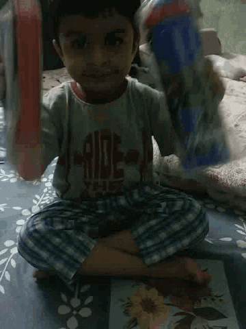 a young boy is sitting on a bed looking at the camera .
