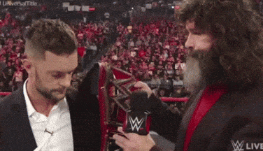 a man with a beard is holding a microphone and talking to another man in a suit .