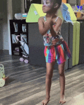 a little girl with face paint on her face is standing on a wood floor
