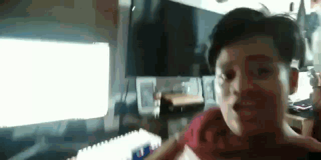 a young boy is making a funny face in front of a computer screen .