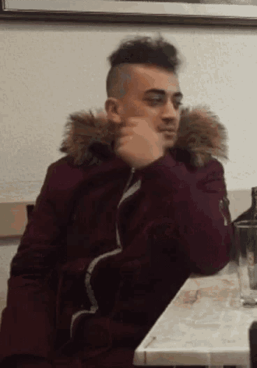 a man wearing a maroon jacket with a fur hood