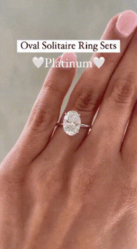 an oval solitaire ring set in platinum is on a woman 's finger