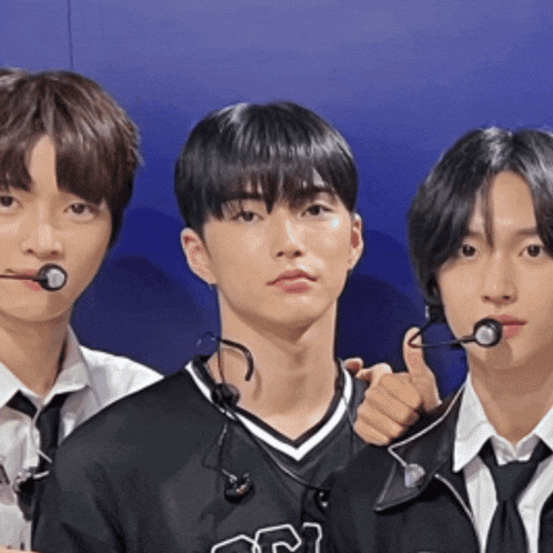 three young men with microphones in their mouths are standing next to each other
