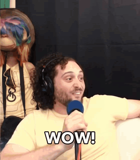 a man wearing headphones holds a microphone and says wow in white letters