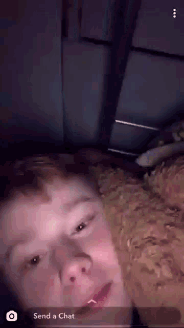 a young man is laying on a bed with a dog and a snapchat message that says " send a chat "