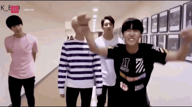a group of young men are standing in a hallway and one of them is wearing a black shirt with the number 7 on it .